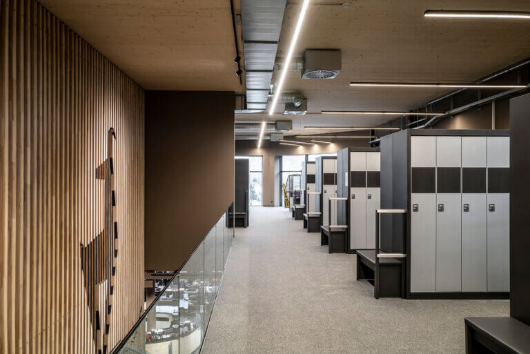 Modernes Ski-Depot mit Holzvertäfelung, Hirsch-Logo und eleganten Schließfächern.