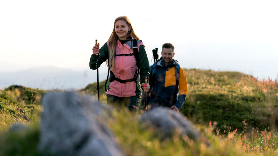Paar wandert mit Trekkingstöcken auf einem Bergpfad. Outdoor-Abenteuerreise.