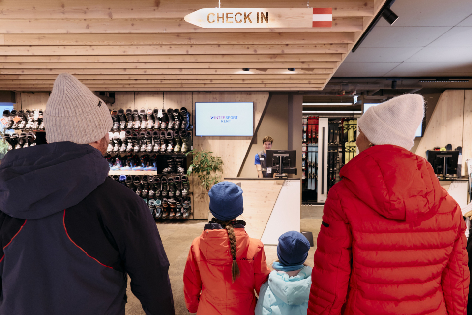 Familie am Check-in-Schalter eines Skiresorts mit Personal; Winterurlaubsreisedienstleistungen.