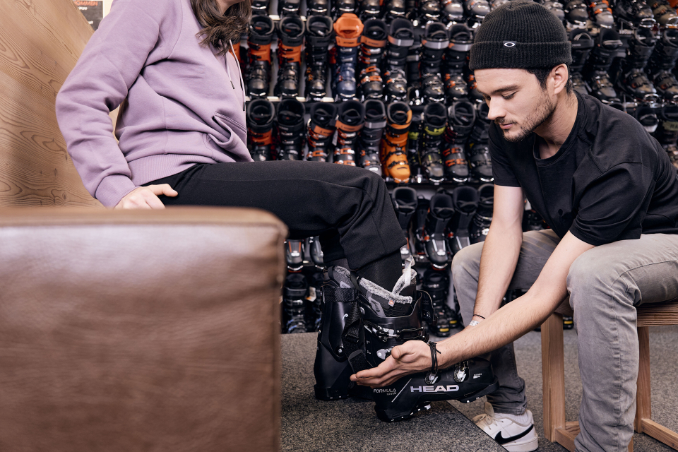 Skiverkäuferin passt einer Frau neue Head Skischuhe für den Wintersport an.