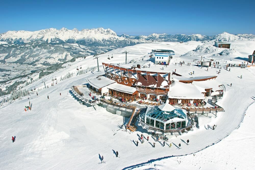 Aerial view of a ski resort with snow-covered buildings, ski lifts, and a distant mountain range. Winter sports destination.