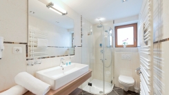 Modernes Badezimmer-Interieur: Waschbecken, Spiegel, Duschkabine, Toilette und beheizter Handtuchhalter.