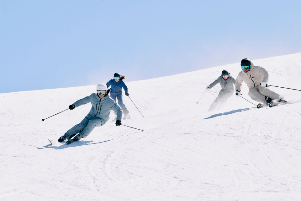 Skigruppe auf schneebedecktem Berggipfel, die einen Skiurlaub in den österreichischen Alpen genießt.