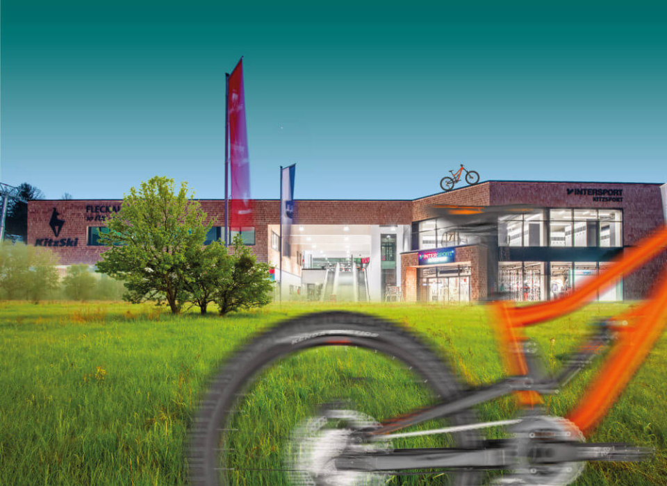 Fahrradladen im Außenbereich mit Mountainbike-Rad im Vordergrund und grünem Rasen.