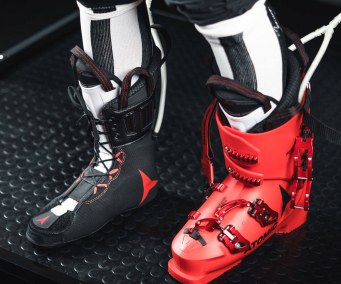 Nahaufnahme von Atomic Skischuhen: ein schwarzer und ein roter, die Skiausrüstung und -zubehör präsentieren.