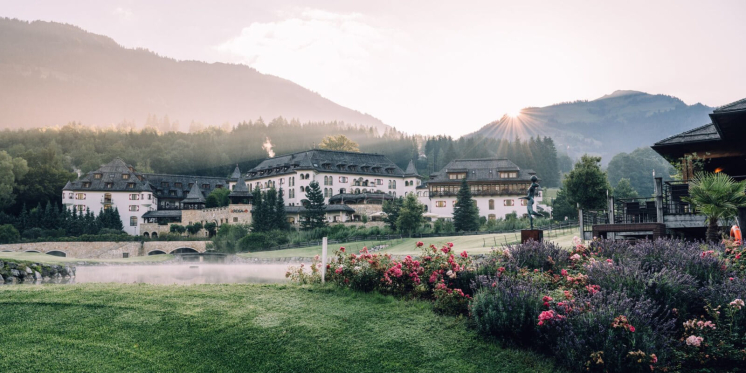 Luxuriöses Hotelresort in den österreichischen Alpen mit Blumengärten und Bergblick bei Sonnenaufgang.