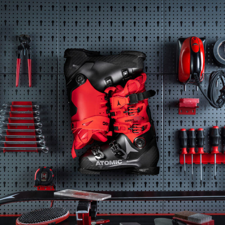 Atomic Skischuhe an einer Werkstatt-Lochwand mit Werkzeugen für die Skischuhanpassung und -wartung.