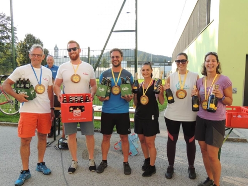 Eine Gruppe von Marathonläufern feiert den Rennsieg mit Bier und Champagner-Medaillen im Freien.