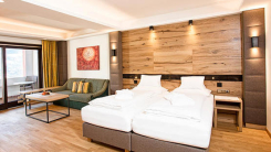 Modernes Hotelzimmer mit Einzelbetten, Sofa, Holzvertäfelung und Zugang zum Balkon. Innenarchitektur.