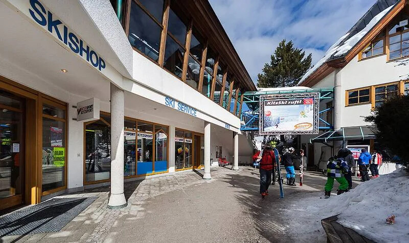 Ski shop entrance in a mountain resort with skiers and winter sports equipment.