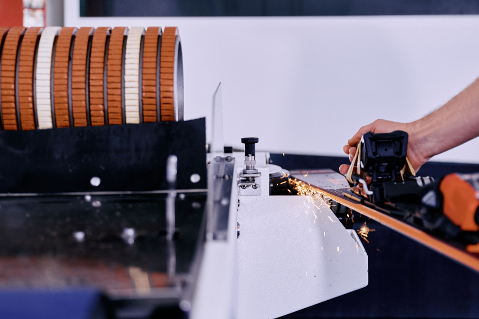 Ski-Tuning: Techniker schärft Skikanten mit einer Schleifscheibe, wobei Funken entstehen.